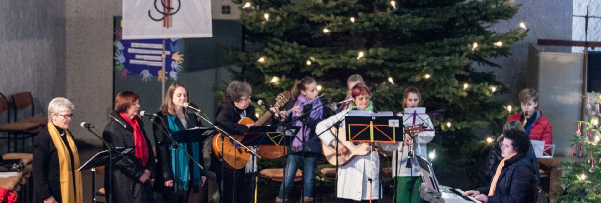 11 Musiker musizieren vor dem Weihnachtsbaum