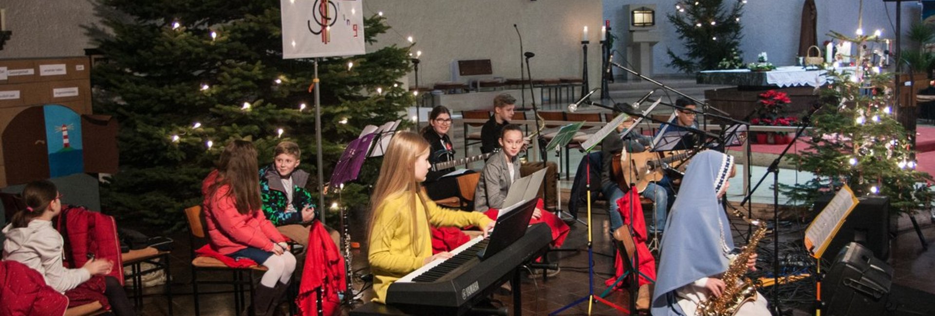 11 Musiker musizieren vor dem Weihnachtsbaum