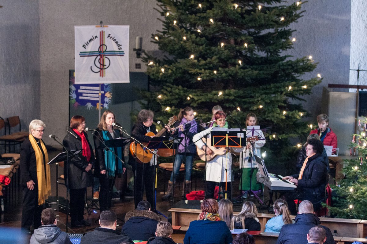 11 Musiker musizieren vor dem Weihnachtsbaum